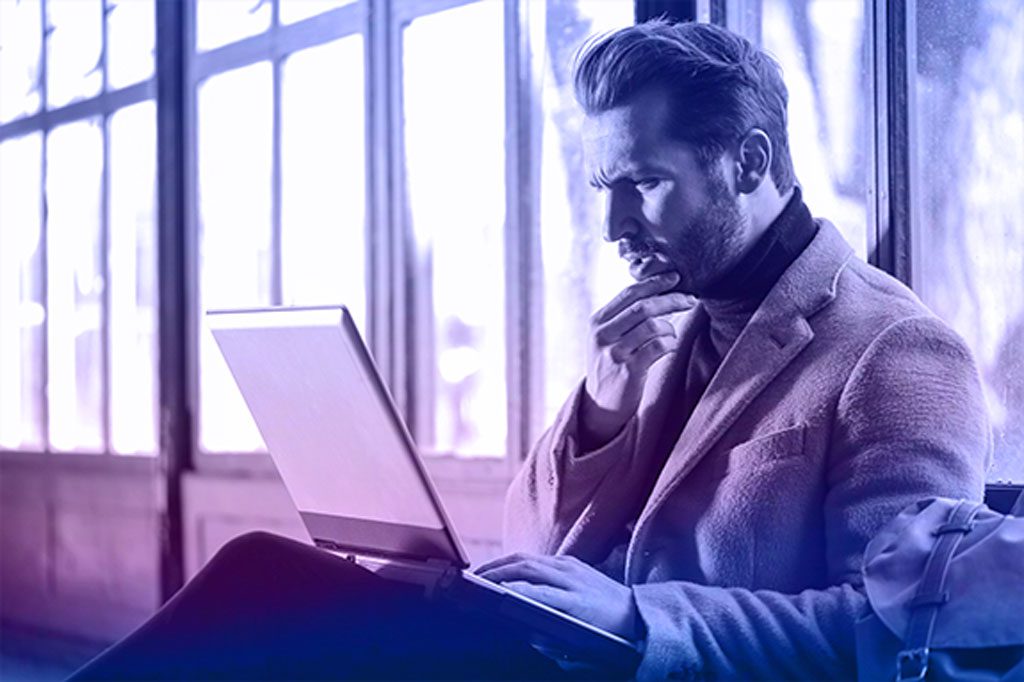 En tenkende mann med en laptop, som vurderer nettstedets markedsførbarhet og digitale strategi.